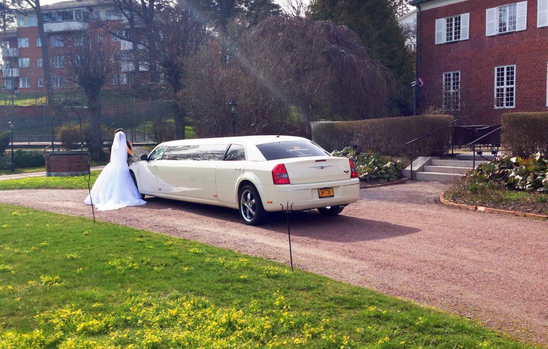 Limousine och brudpar står i en park i Stockholm för att ta bilder.